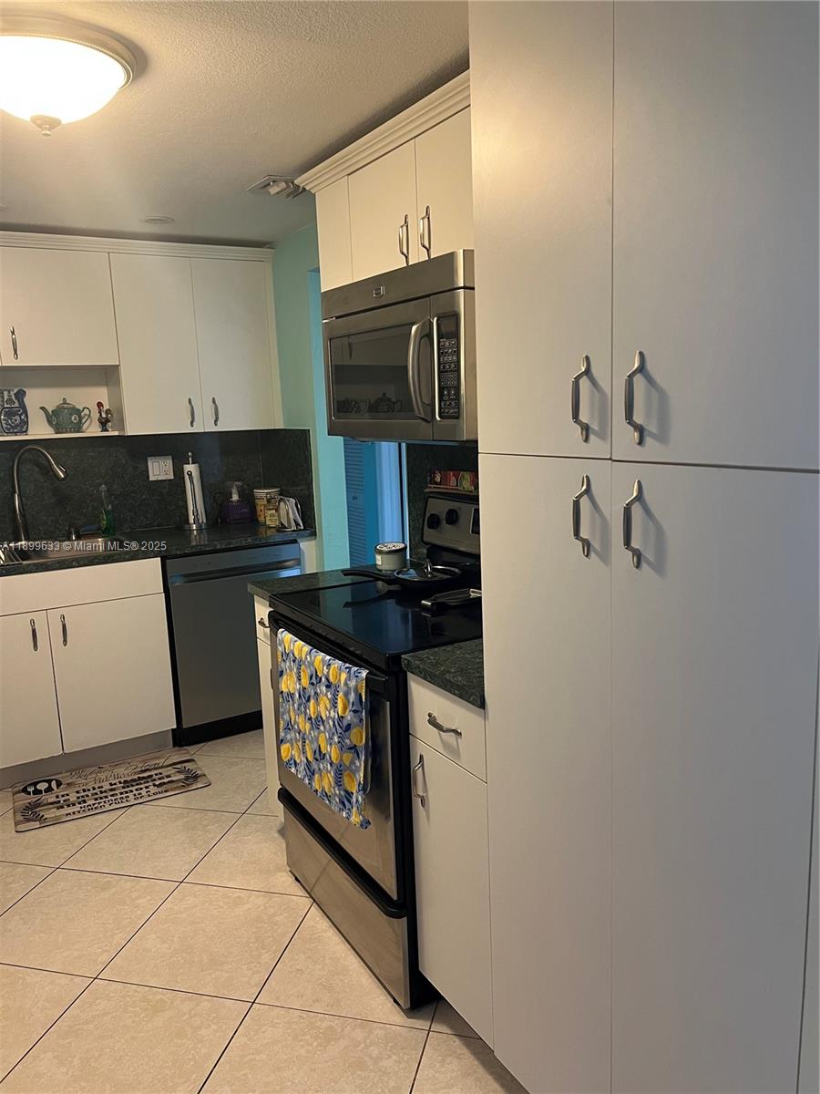 8335 Southwest 72nd Avenue, Unit 212D Miami, FL 33143 - Photo 10 of 31 a kitchen with stainless steel appliances granite countertop a sink and a stove