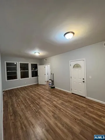 a view of empty room with wooden floor and window