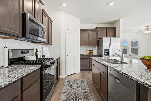 a kitchen with stainless steel appliances granite countertop a sink stove microwave and refrigerator