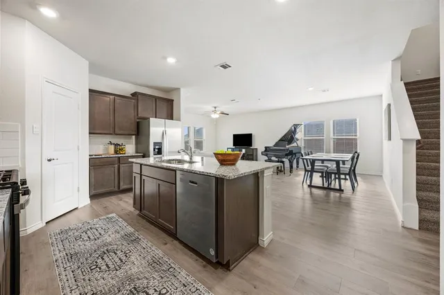 a kitchen with stainless steel appliances kitchen island granite countertop a stove top oven a sink a dining table and chairs