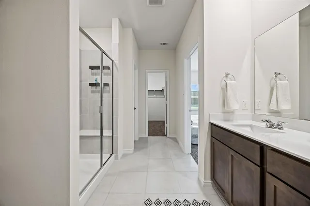 a spacious bathroom with a double vanity sink a mirror and a shower