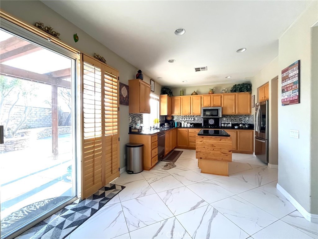 24336 Caladium Place Valencia, CA 91354 - Photo 5 of 25 a large kitchen with stainless steel appliances kitchen island granite countertop a refrigerator a oven a sink and a large window