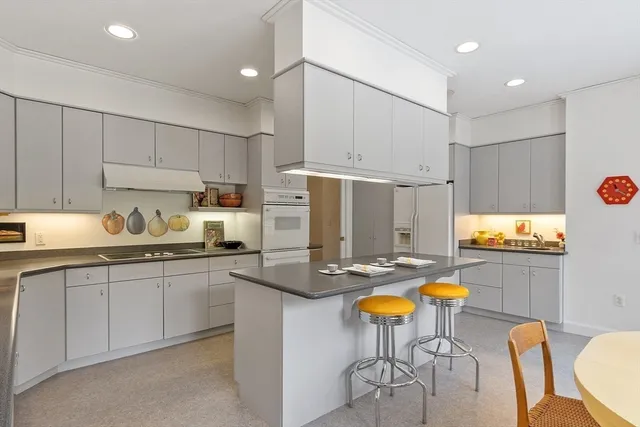 a kitchen with stainless steel appliances kitchen island granite countertop a sink a stove a dining table and chairs