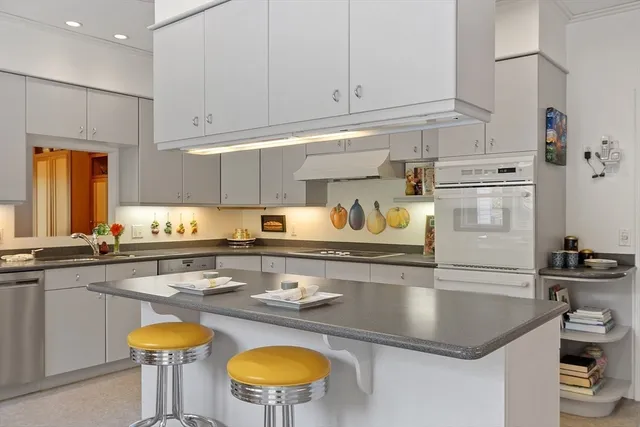 a kitchen with stainless steel appliances granite countertop a sink a stove and white cabinets