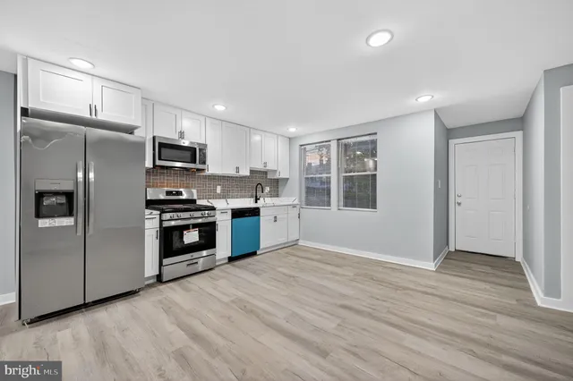 a kitchen with granite countertop a refrigerator and a stove top oven