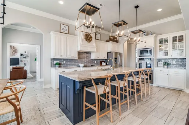 a kitchen with stainless steel appliances kitchen island granite countertop a table chairs and a refrigerator