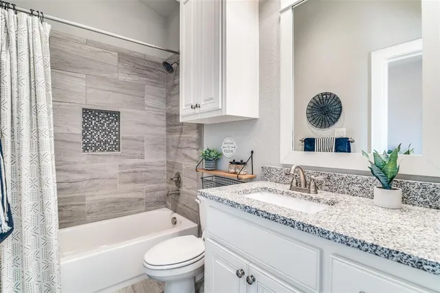 a bathroom with a granite countertop sink a toilet a mirror and shower