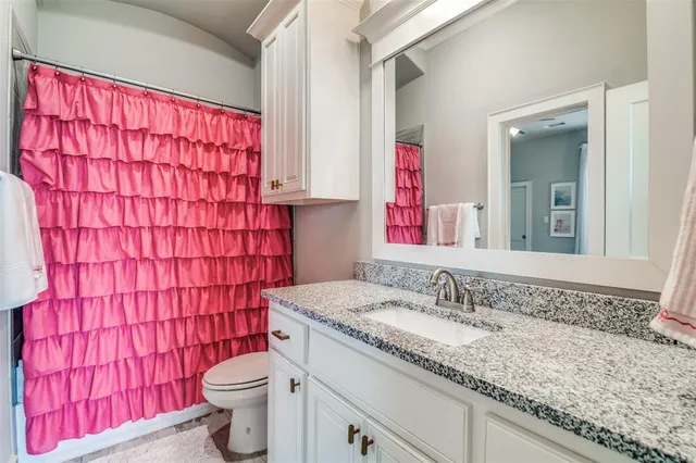 a bathroom with a granite countertop toilet sink and mirror