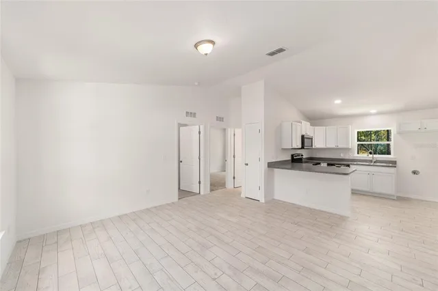 a large white kitchen with white cabinets and wooden floor