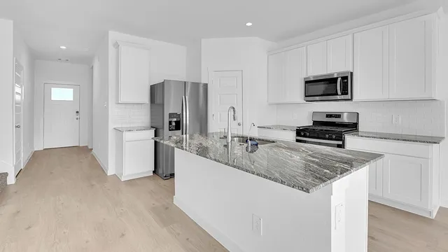 a kitchen with stainless steel appliances granite countertop a sink stove and refrigerator