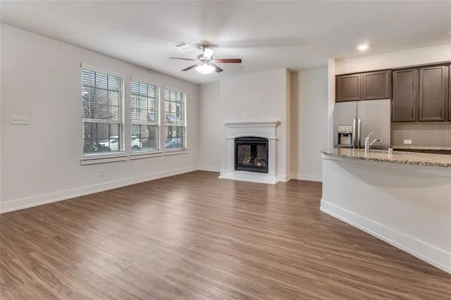 a view of an empty room with wooden floor and a kitchen
