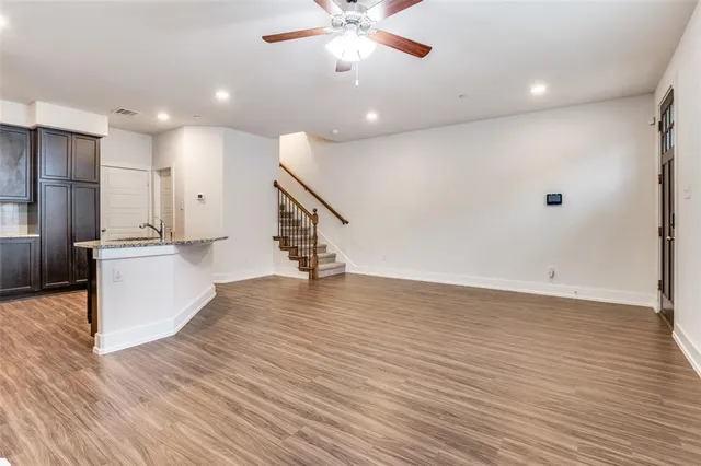 a view of an empty room with wooden floor and a ceiling fan