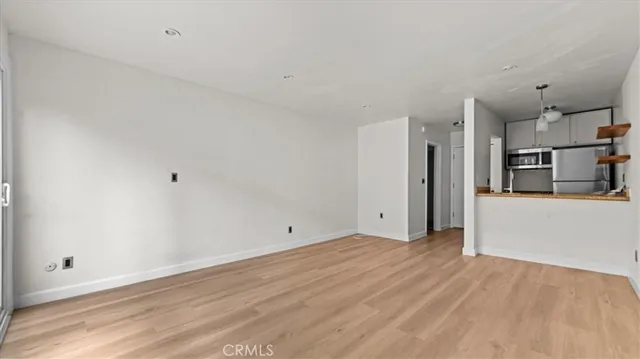 a view of a kitchen with refrigerator and wooden floor