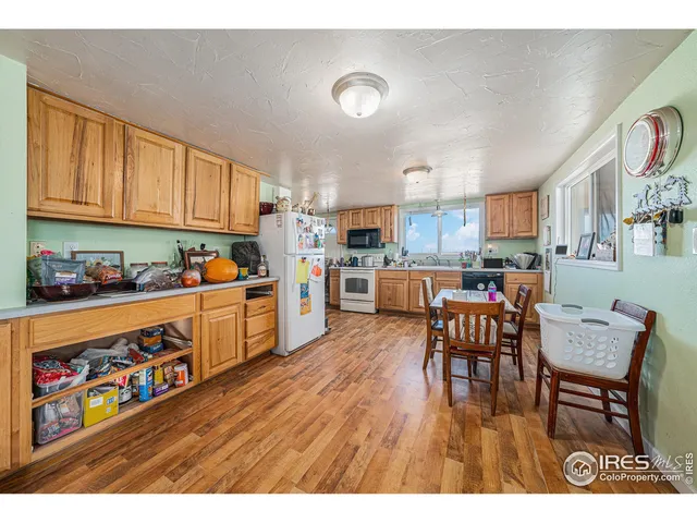 a open kitchen with stainless steel appliances granite countertop a refrigerator oven a sink dishwasher and white cabinets with wooden floor