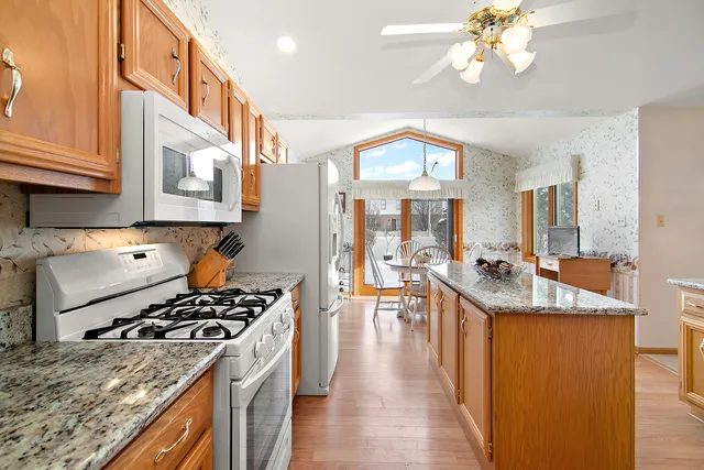 a kitchen with stainless steel appliances granite countertop a stove and a view of living room