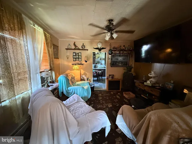 a living room with furniture a ceiling fan and a large window