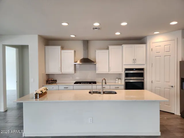 a kitchen with kitchen island a sink a stove a refrigerator and white cabinets
