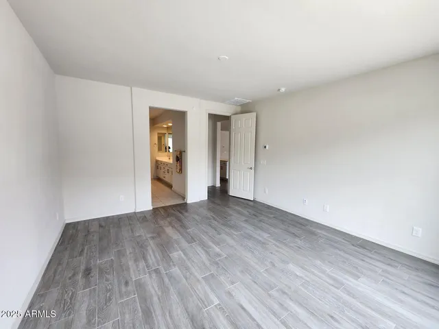 a view of an empty room with wooden floor and window