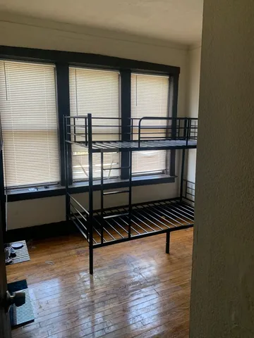 a bedroom with wooden floor and a window
