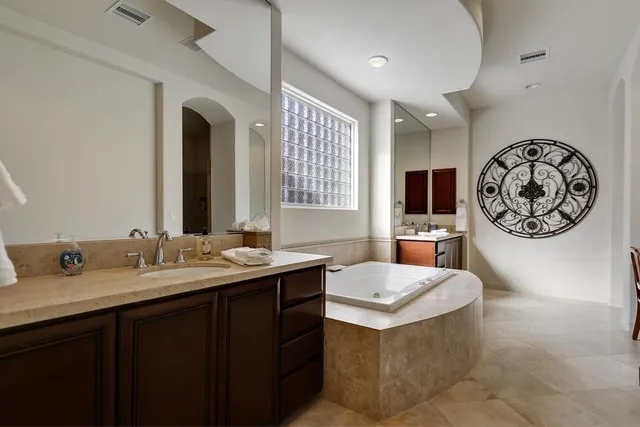 a spacious bathroom with a tub double sink and a large mirror