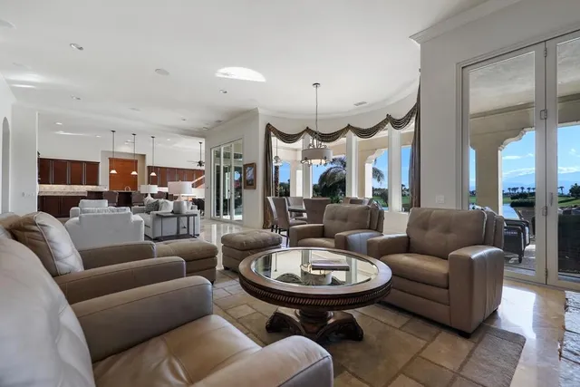 a living room with furniture kitchen view and a chandelier