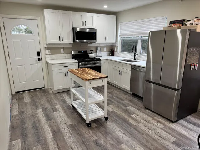 a kitchen with a refrigerator a stove top oven a sink and dishwasher with wooden floor