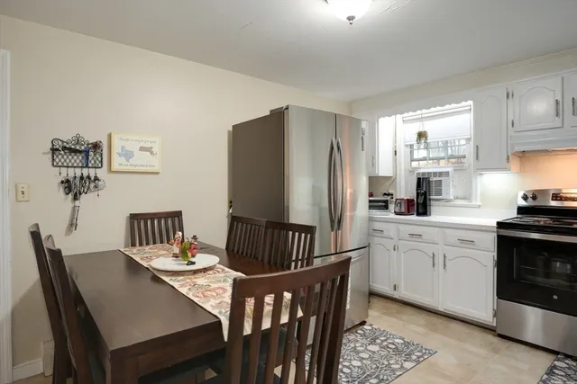 a kitchen with stainless steel appliances granite countertop a dining table chairs refrigerator and sink