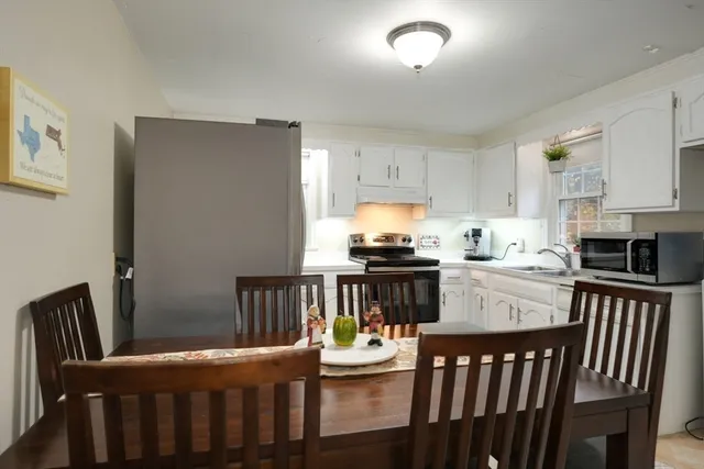 a kitchen with kitchen island granite countertop a refrigerator a stove top oven a sink dishwasher and white cabinets next to a window