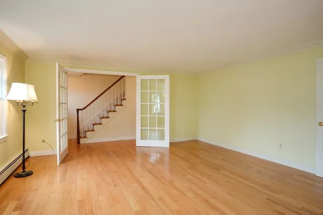 a view of an empty room with wooden floor and stairs