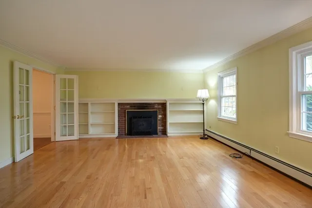a view of an empty room with a window and wooden floor