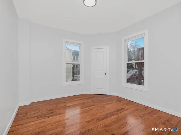 a view of an empty room with wooden floor and window