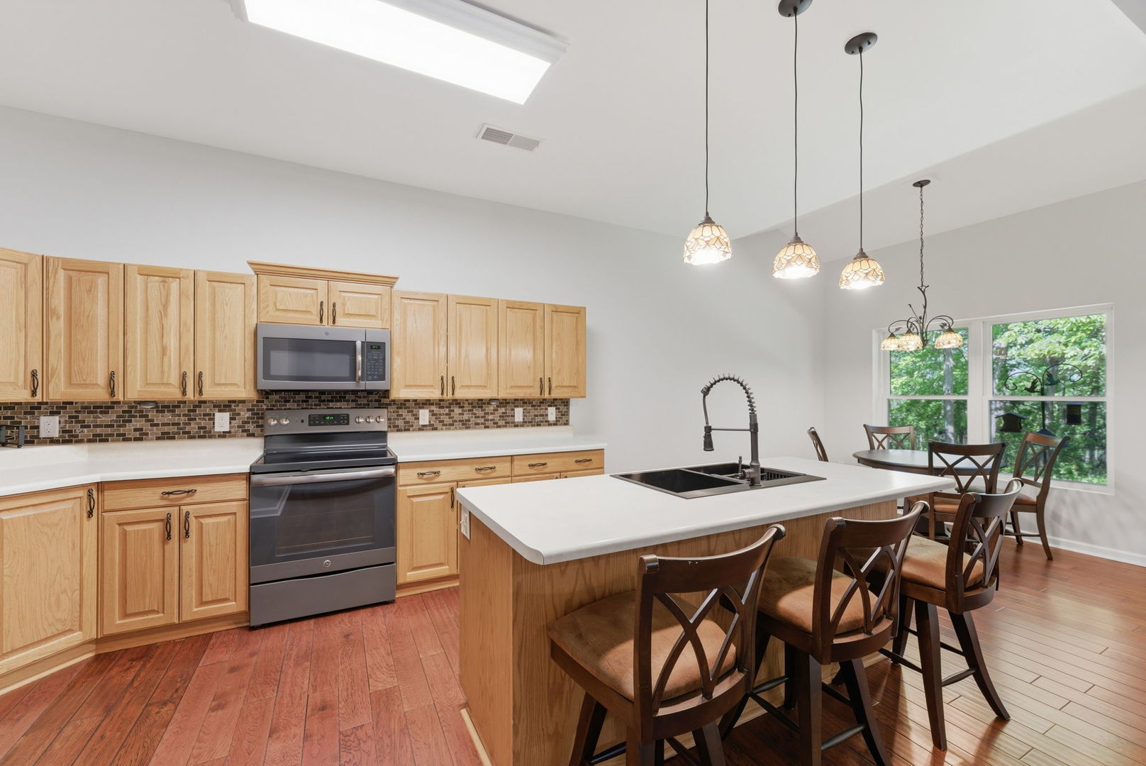1002 2nd St Court Moline, IL 61265 - Photo 12 of 31 a kitchen with stainless steel appliances granite countertop a stove a sink a microwave a dining table and chairs with wooden floor
