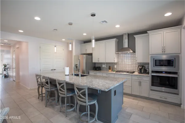 a kitchen with stainless steel appliances granite countertop a table chairs sink refrigerator and microwave
