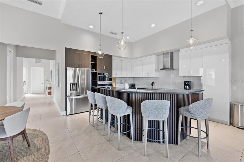 7580 Excitement Drive Reunion, FL 34747 - Photo 11 of 47 a kitchen with stainless steel appliances kitchen island granite countertop a dining table chairs and a refrigerator