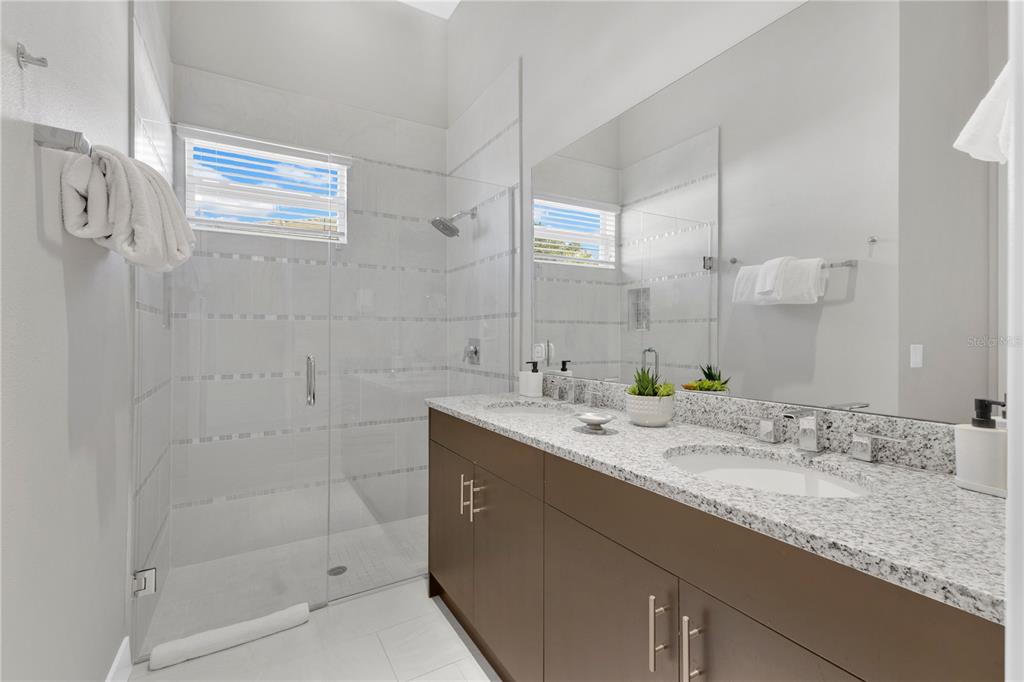 7580 Excitement Drive Reunion, FL 34747 - Photo 27 of 47 a bathroom with a granite countertop sink mirror and shower