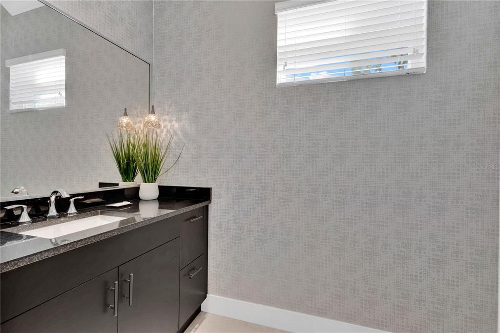 7580 Excitement Drive Reunion, FL 34747 - Photo 29 of 47 a bathroom with a granite countertop sink a mirror and vanity