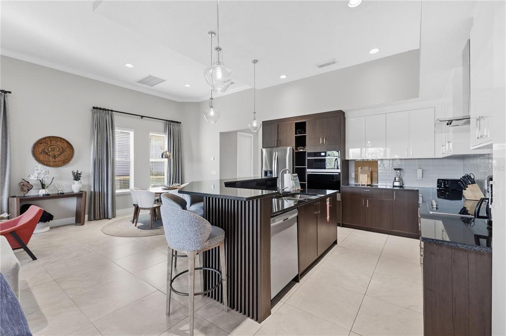 7580 Excitement Drive Reunion, FL 34747 - Photo 10 of 47 a kitchen with stainless steel appliances granite countertop a stove top oven a sink dishwasher a dining table and chairs with wooden floor
