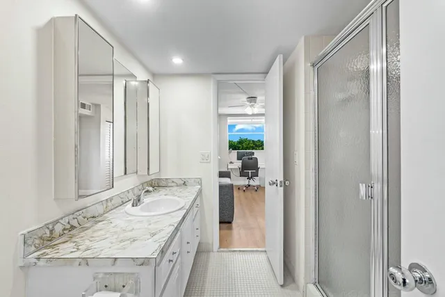 a bathroom with a granite countertop sink mirror and shower