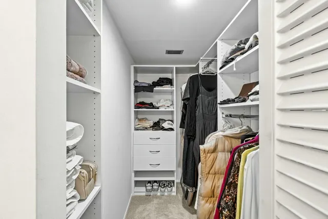 a view of walk in closet with clothes and shoes