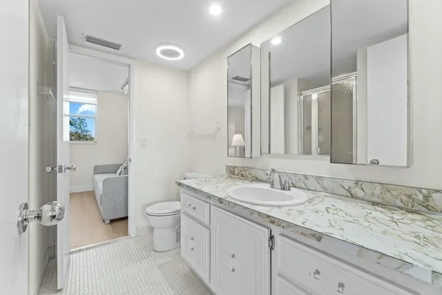 a bathroom with a granite countertop sink a toilet and a mirror