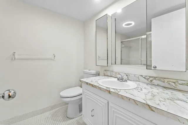 a bathroom with a granite countertop sink a toilet and a mirror
