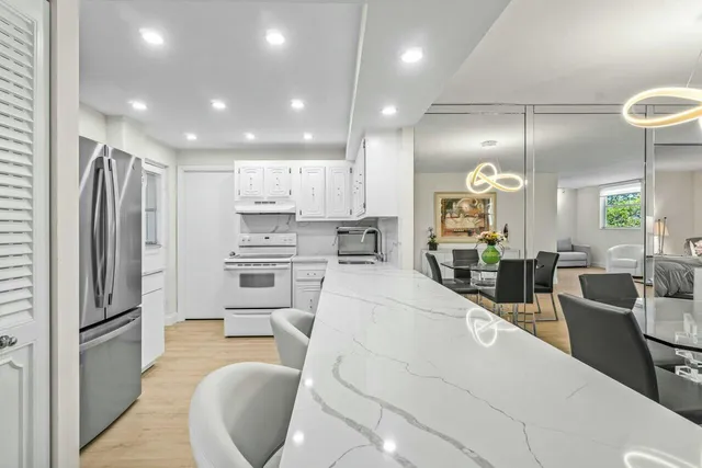 a large kitchen with stainless steel appliances kitchen island granite countertop a refrigerator and a stove top oven