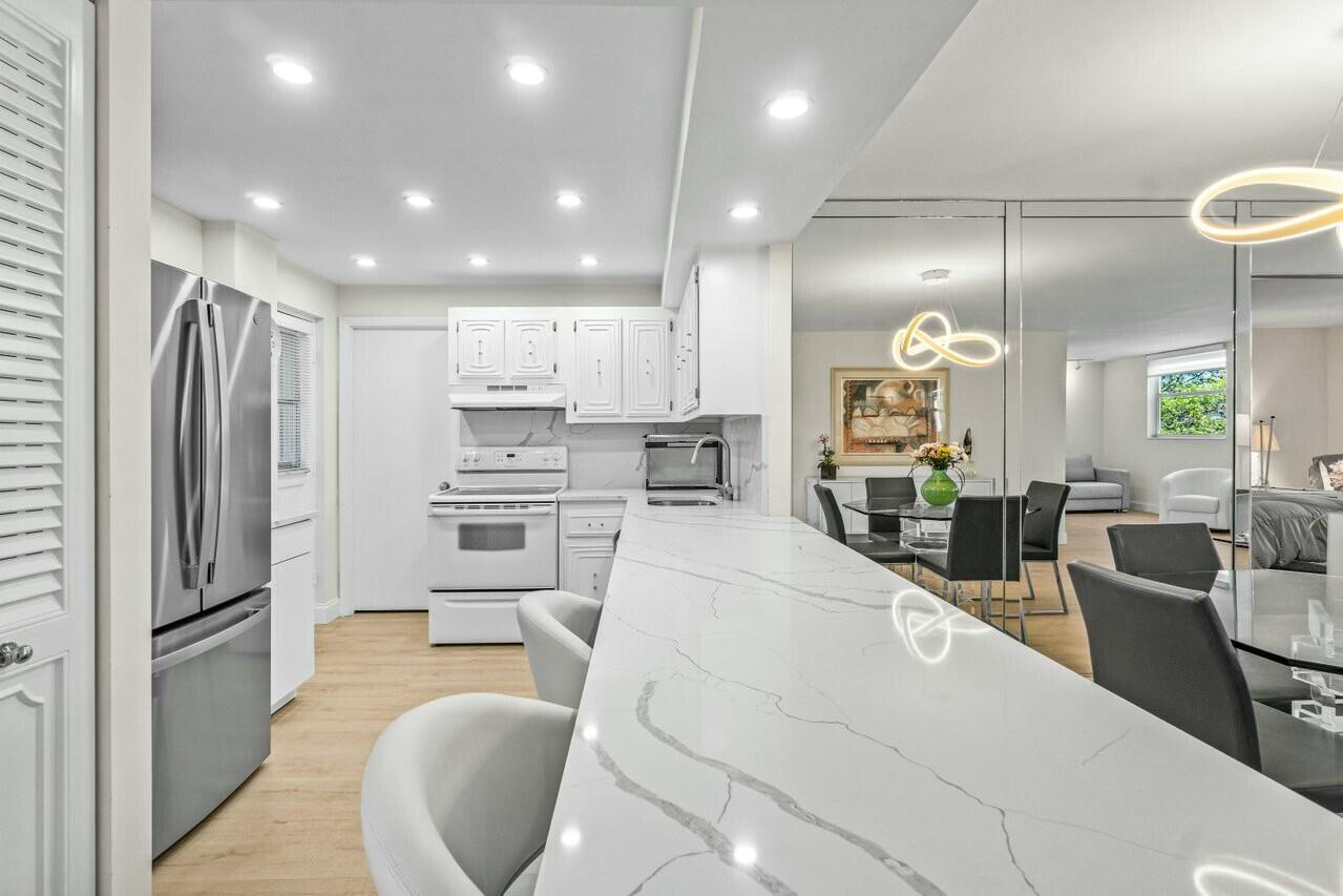 6461 Northwest 2nd Avenue, Unit 411 Boca Raton, FL 33487 - Photo 3 of 34 a large kitchen with stainless steel appliances kitchen island granite countertop a refrigerator and a stove top oven