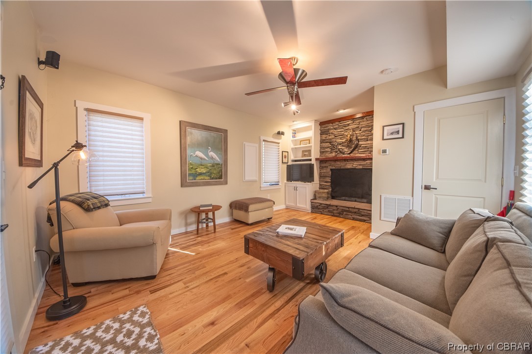 1239 Kelley Neck Road Lancaster, VA 22503 - Photo 21 of 48 Living room featuring a stone fireplace, built in shelves, light hardwood / wood-style floors, and ceiling fan