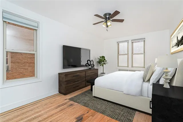 a bedroom with a bed a window and potted plant on a dresser
