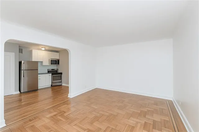 a view of an empty room and kitchen view