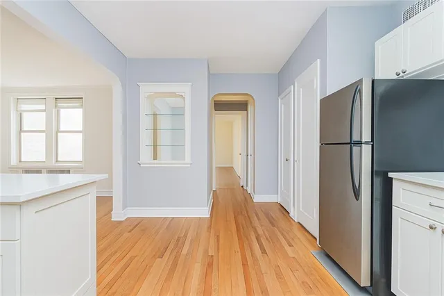a view of a kitchen with a refrigerator a sink a kitchen and wooden floor