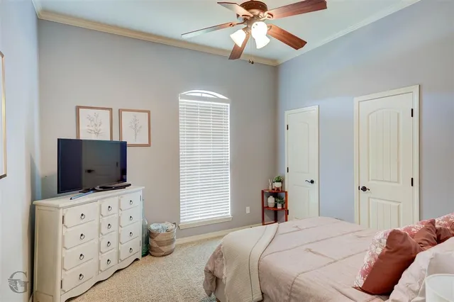 a bedroom with a bed and a flat tv screen on dresser