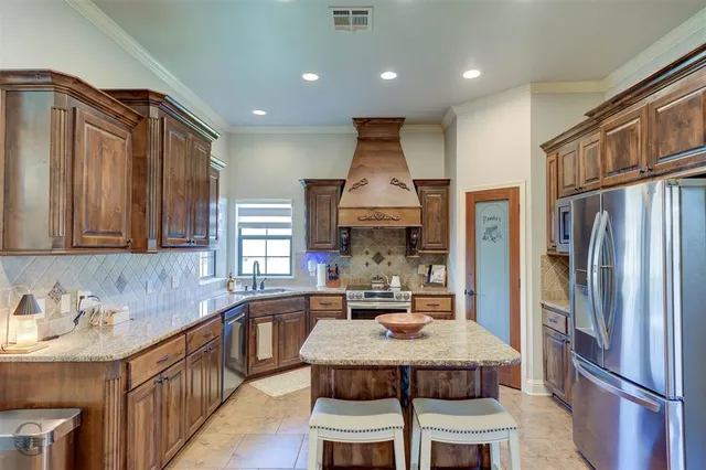 a kitchen with stainless steel appliances kitchen island granite countertop a sink refrigerator and cabinets