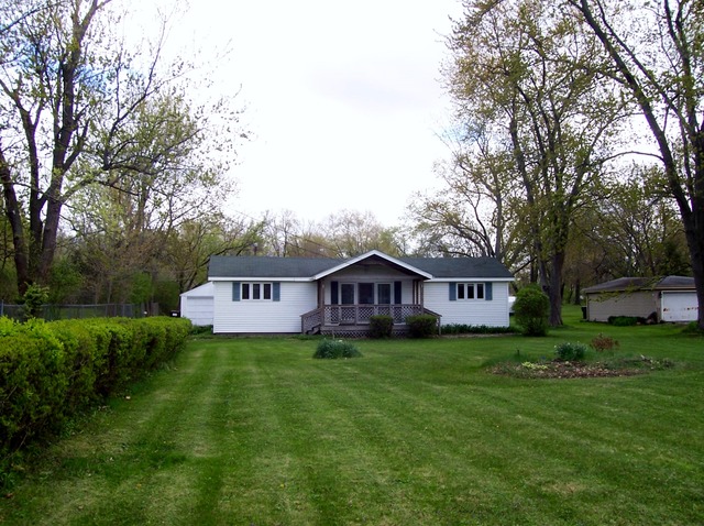 3645 Flossmoor Road Homewood, IL 60422 - Photo 8 of 10 a house that is sitting in the grass with large trees and plants